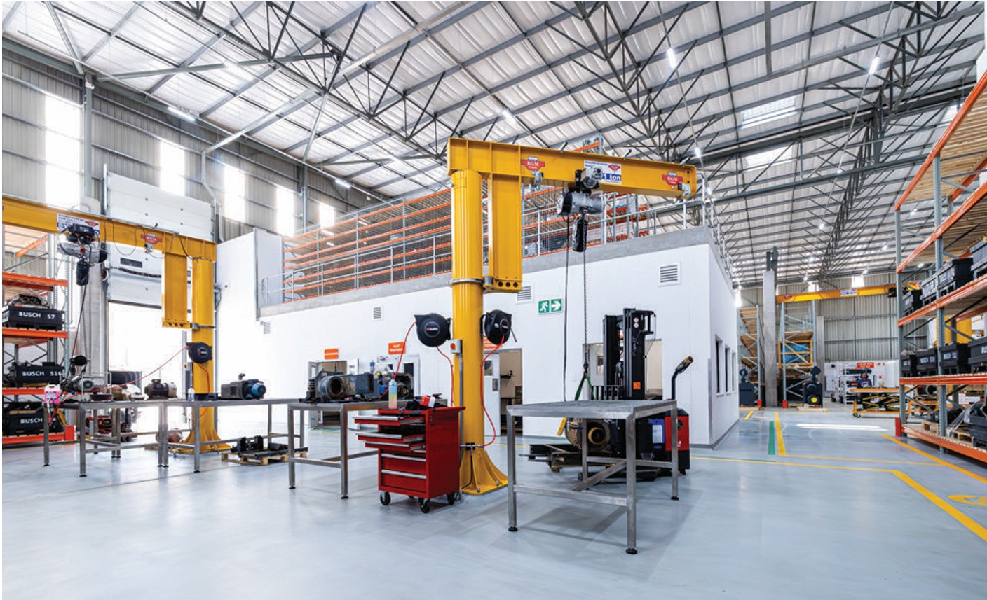Large industrial air compressor with pipes, gauges, and heavy-duty equipment on a factory floor